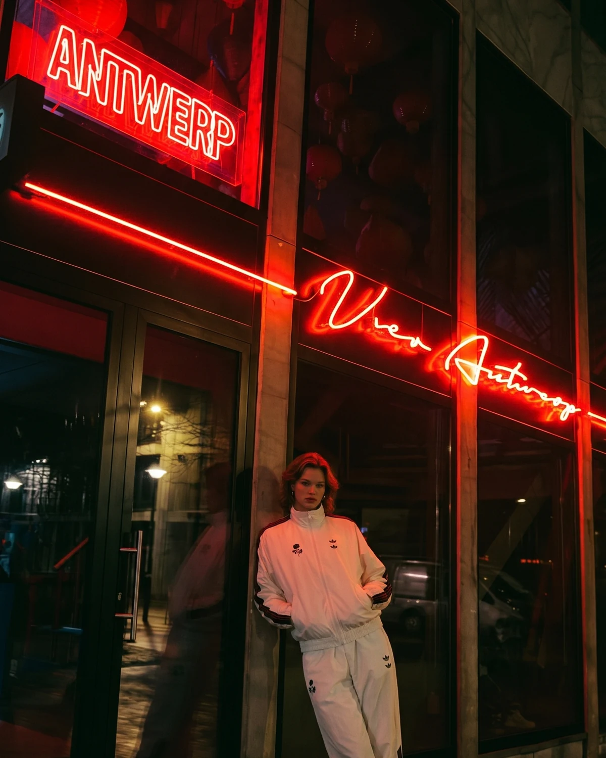 Red Antwerp storefront visual with model in white tracksuit